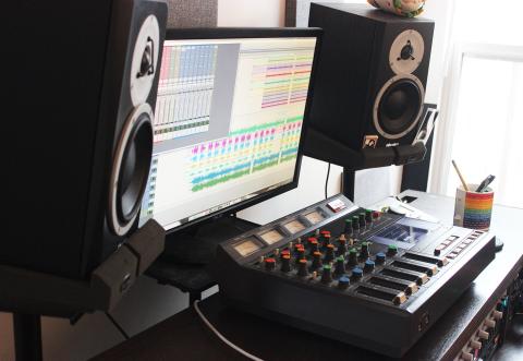 Home studio set up with mixing console, monitor, and speakers on either side