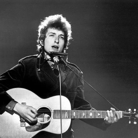 Black and white image of a young Bob Dylan performing onstage