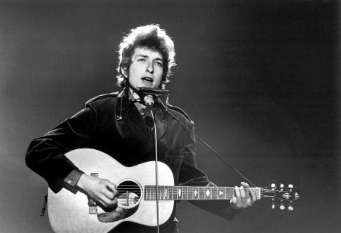 Black and white image of a young Bob Dylan performing onstage
